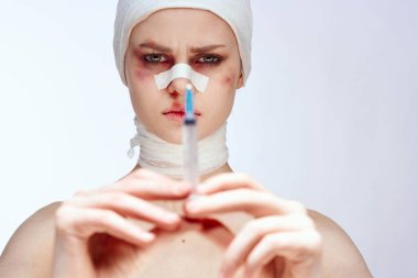 Yüzü bandajlı bir insan, elinde şırınga, elinde ağrı kesici, stüdyo hayatı tarzında çürükler bırakır.