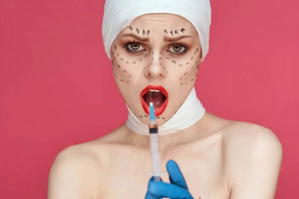 Žena pózuje v modrých rukavicích červené rty chirurgie obličeje omlazení růžové pozadí — Stock fotografie