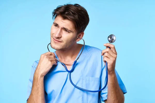 Uomo in uniforme medico trattamento sanitario stetoscopio esame sfondo blu — Foto Stock