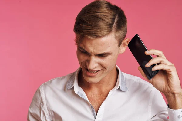 Portrét muže v bílé košili mluvící po telefonu růžové pozadí — Stock fotografie