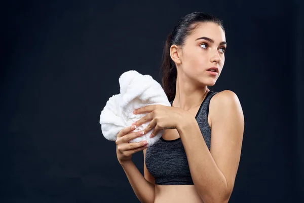 Donna atletica con asciugamano bianco palestra figura sottile sfondo scuro — Foto Stock