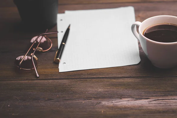 Ноутбук с ручкой кофе чашки бумаги аксессуары деревянный стол — стоковое фото