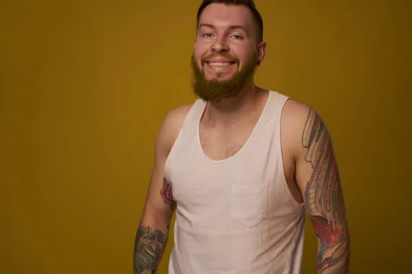 Macho muž v bílém tričku tetování na pažích představuje izolované pozadí — Stock fotografie