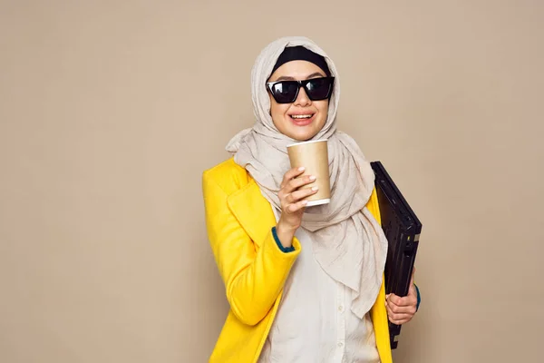 Femme en lunettes de soleil en hijab une tasse de café fond beige — Photo