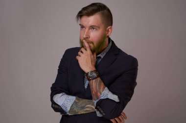 Ceketli sakallı adam profesyonel poz veriyor.