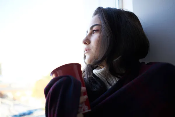 Kvinna nära fönster med röd kopp depression närbild — Stockfoto