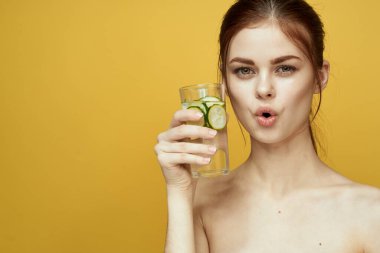 Salatalıklı kadın vitamin içer vücut bakımı sarı arka plan