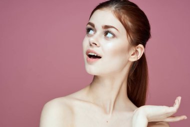 Çıplak omuzlu, çekici, pembe arka planı olan bir kadın.