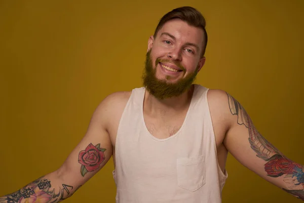 Cheerful bearded man in a white T-shirt with hooligan tattoos on his arms — Stock Photo, Image