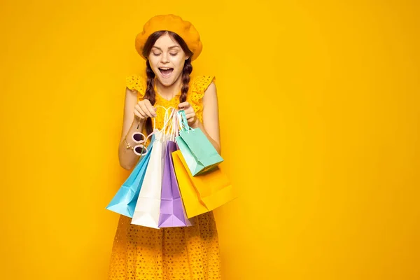 Femme gaie avec des sacs multicolores posant fond jaune — Photo