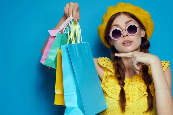 戴着太阳镜的快乐女人摆出购物时尚的蓝色背景 — 图库照片