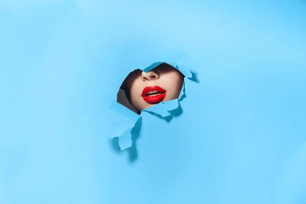 Mulher espreitando através dos buracos no cartaz azul estúdio fundo — Fotografia de Stock