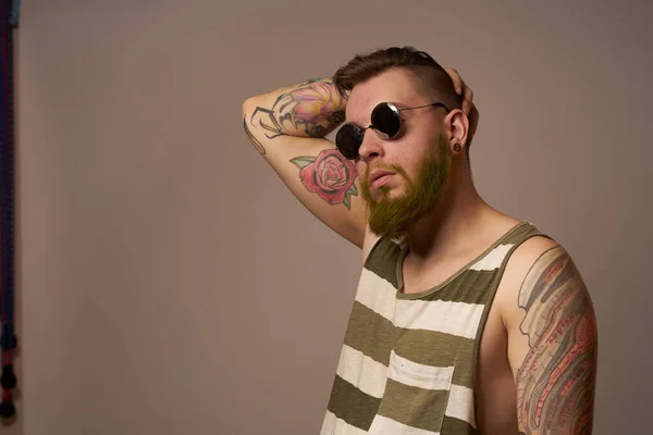 Homme barbu en t-shirt rayé lunettes tatouage sur ses bras mode — Photo