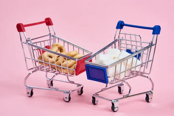 Küçük alışveriş arabaları süpermarket alışverişi pembe arka plan — Stok fotoğraf