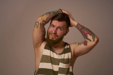 Kollarında dövmeleri olan yakışıklı bir adam. Saç stili duyguları var.