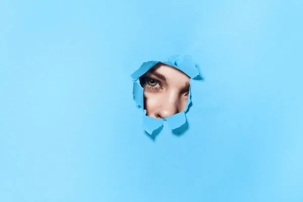 Poster mavisi stüdyo arka planındaki deliklerden bakan bir kadın. — Stok fotoğraf