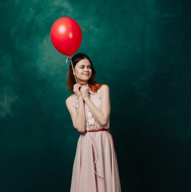 Kırmızı balonlu kadın yeşil arka planda tatil eğlencesi