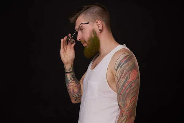 Hombre barbudo en camiseta blanca con tatuajes en sus brazos posando bravucón — Foto de Stock