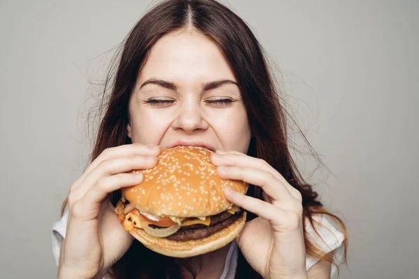 Mujer con una hamburguesa en sus manos un bocadillo de comida rápida de cerca —  Fotos de Stock