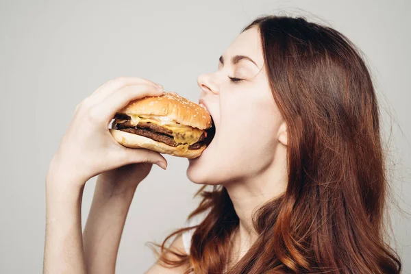 Femme avec un hamburger dans ses mains une collation fast food close-up — Photo