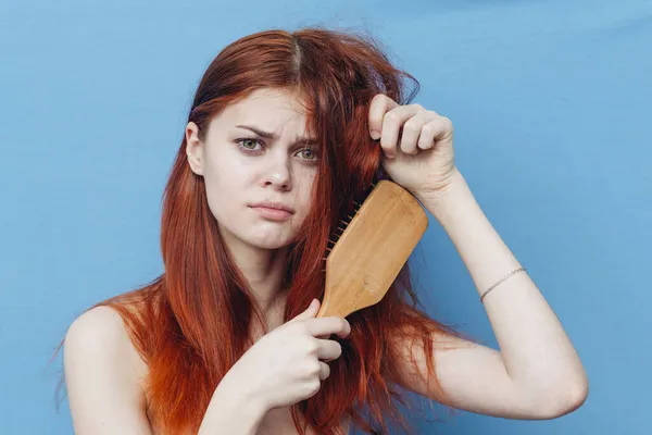 Hezká žena česání zlobivé vlasy modré pozadí — Stock fotografie