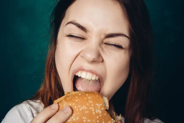 Vrouw eten hamburger fast food snack close-up — Stockfoto