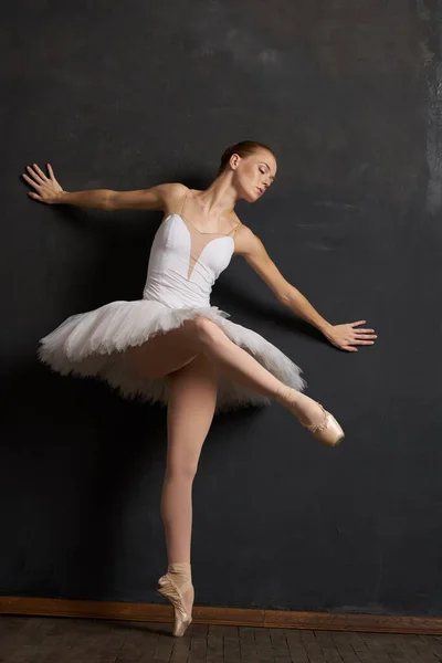 하얀 턱시도 춤을 추는 여성 발레리나의 어두운 배경 공연 — 스톡 사진