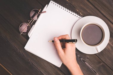 Bir fincan kahve, not defteri, kafenin sapı, yukarıdan manzara.