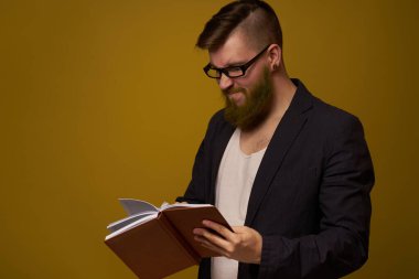 Gözlüklü bir iş adamı, bir stüdyo görevlisinin elinde not defteri.