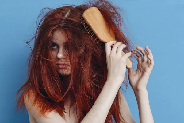 Mulher emocional pentear seu cabelo bagunçado fundo azul — Fotografia de Stock