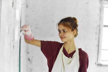 Beyaz önlüklü ev dekorasyonu yapan neşeli kadın ressam.