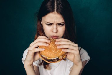 Hamburgerli neşeli kadın fast food yiyor.