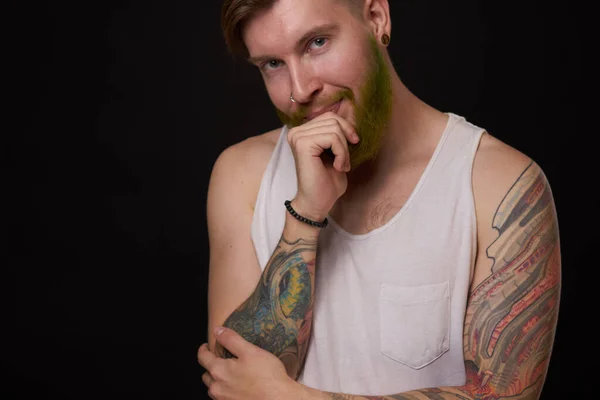 Bearded man with tattoos on his arms gesturing with his hands dark background — Stock Photo, Image