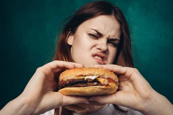 Mujer alegre con hamburguesa cerca de la cara snacking comida rápida —  Fotos de Stock