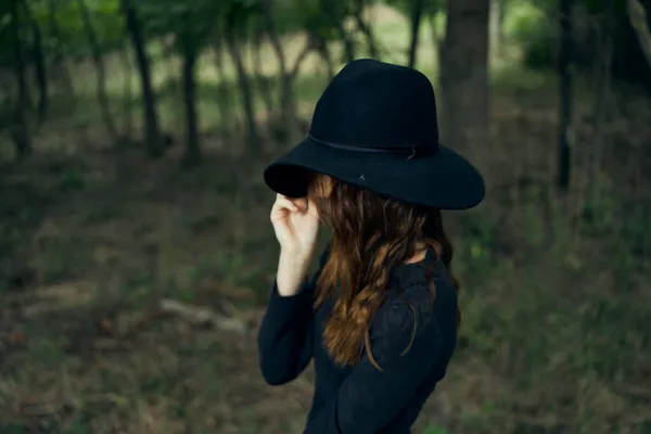 Mulher bruxa de chapéu preto na floresta posando fantasia — Fotografia de Stock