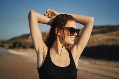 Siyah mayo giymiş güzel bir kadın kumsalda güneşleniyor.