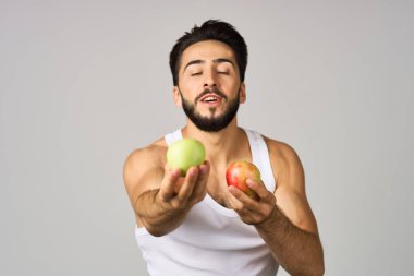 Beyaz tişörtlü bir adam. Meyve diyeti. Hafif arka plan.