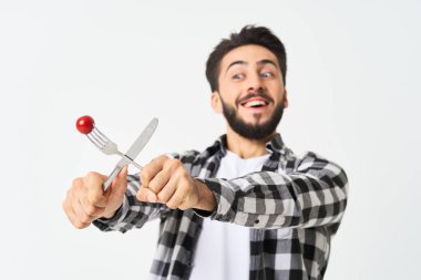 Mutfak aletleriyle sakallı adam. Kiraz domatesli atıştırmalık.