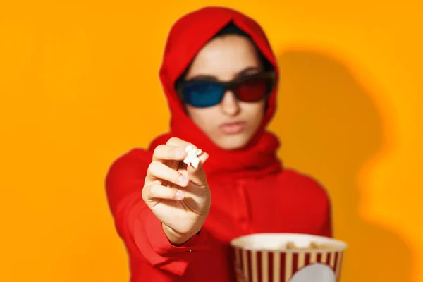 赤いヒジャーブ3Dメガネ技術を持つ女性映画ポップコーン黄色の背景を見て — ストック写真