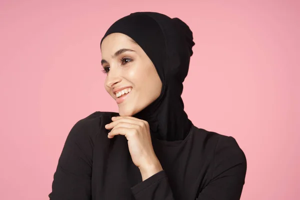 Весёлая мусульманка чёрный хиджаб позирует рукой жестом розового фона — стоковое фото