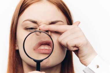 Güzel bir kadın büyüteçle yüzünü buruşturuyor.