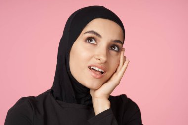 neşeli Müslüman kadın siyah tesettüre poz veren el hareketi pembe arka plan