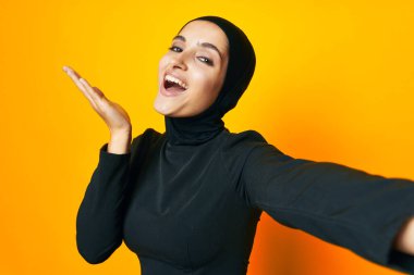 Güzel bir kadın etnik köken modeli duygularını sarı arka planda gösteriyor.