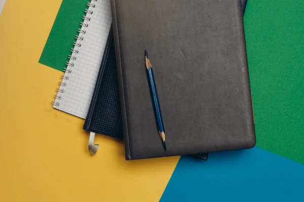 Preto notepad lápis colorido fundo material de escritório — Fotografia de Stock