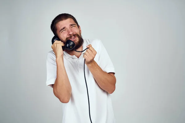 Emotional bearded man talking on retro phone light background — Stock Photo, Image