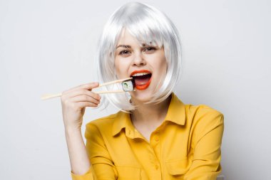 Beyaz peruklu güzel bir kadın ve Japon yemek çubuklarıyla suşi.