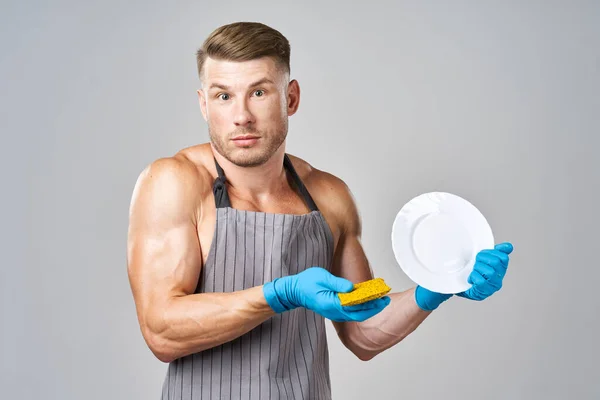 Een man in een schort die de afwas doet — Stockfoto