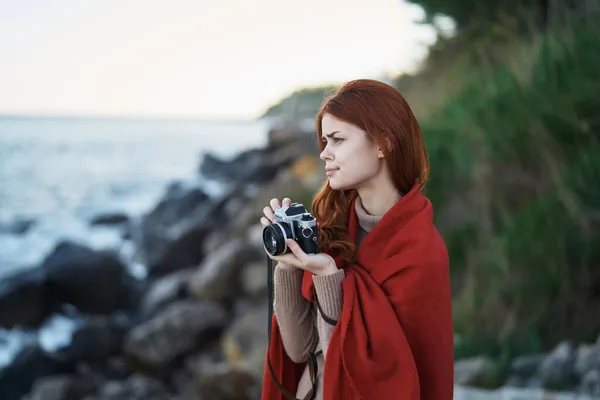 Mulher se escondendo com um cobertor na natureza com uma câmera de férias fotógrafo viagem — Fotografia de Stock