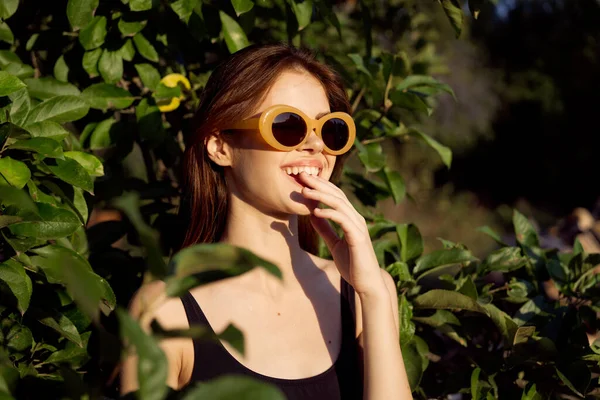 Vidám nő visel napszemüveg zöld levelek természet nyári pózol — Stock Fotó
