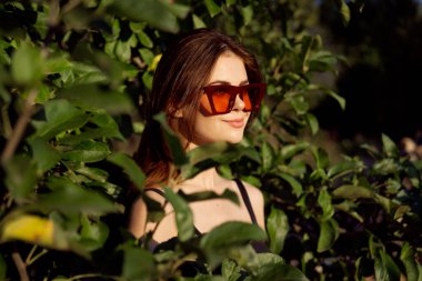 Yazın açık havada çekici bir kadın. Yeşil yapraklar moda.
